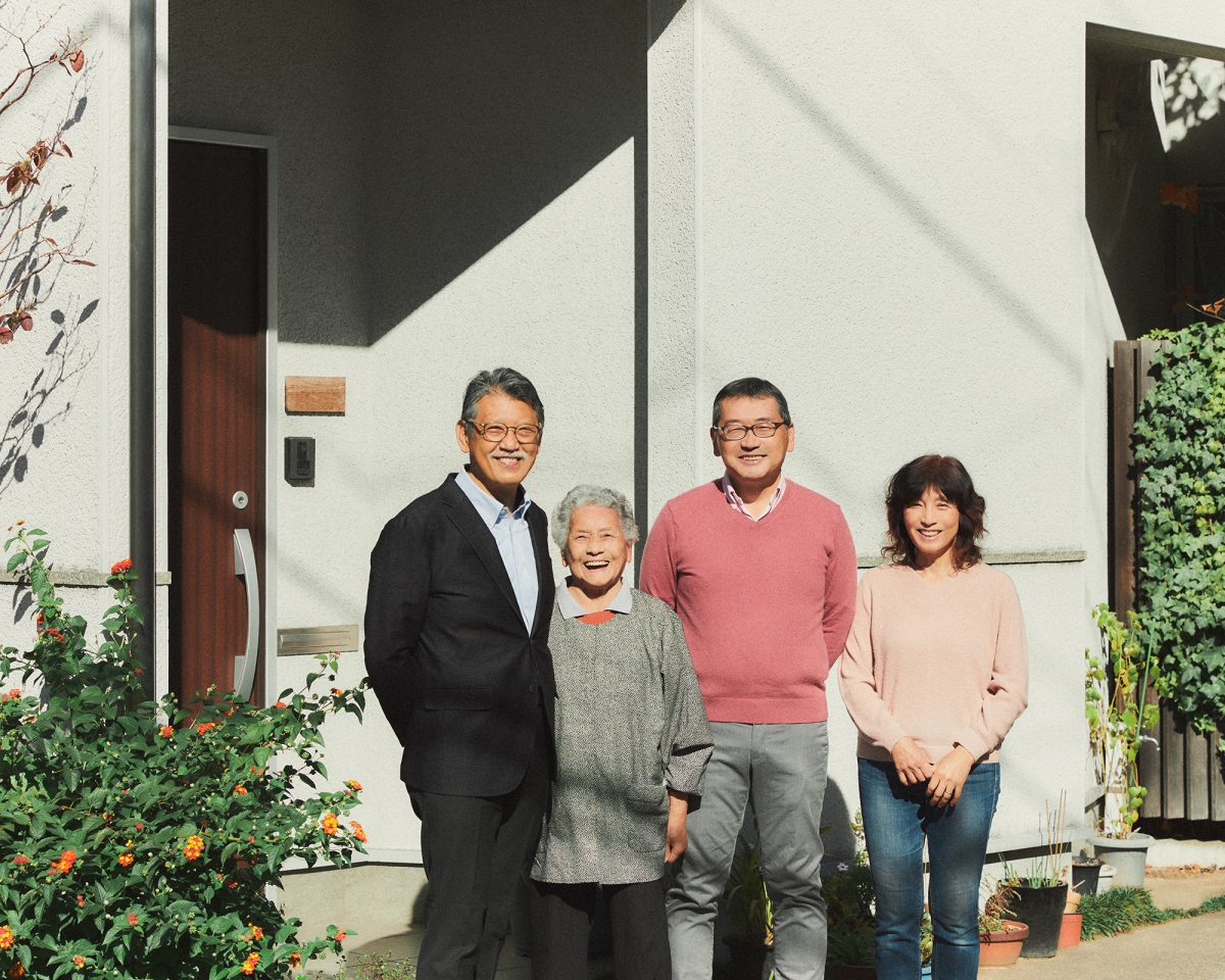 完成した住まいの前でお客様と笑顔を見せる担当者